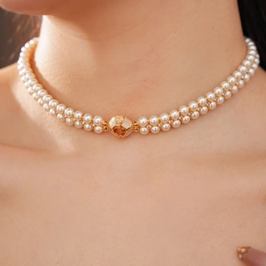 Détail d'un collier de perles blanches à double rangée avec fermoir doré sur le mannequin