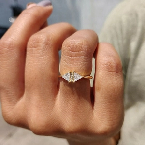 Detail of a gold triangle ring with micro-inset zircons worn on a model's hand