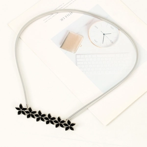 Close-up of elastic silver metal waist chain featuring black flower motifs on ivory background