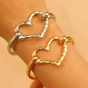 Close-up of hammered gold and silver hollow heart bangles with unique lava texture