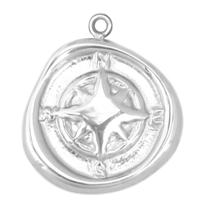 Macro shot of silver compass pendant with wax seal edges and engraved cardinal directions