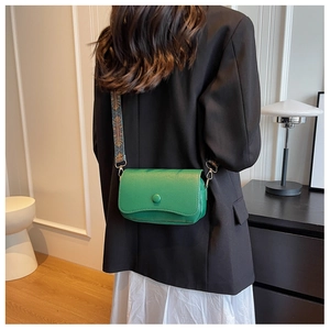 Detail view of green leather crossbody bag with textured finish and patterned wide strap