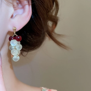 Close-up of red and white resin grape tassel earrings on a model in a minimal setting