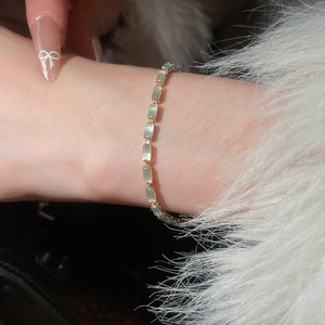 Macro shot of emerald-cut sea blue zircon bracelet in gold plating on wrist
