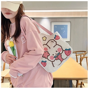 Detail view of a white canvas tote bag with a cute cartoon rabbit and peach print design