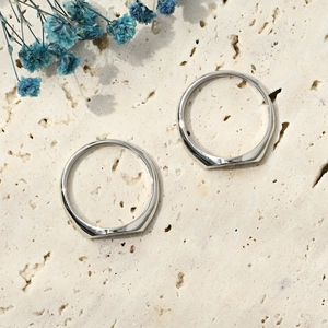 Detail of silver sun and moon couple rings on a minimalist stone background