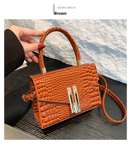 Brown crocodile embossed handbag featuring golden metal buckle and retro flap design
