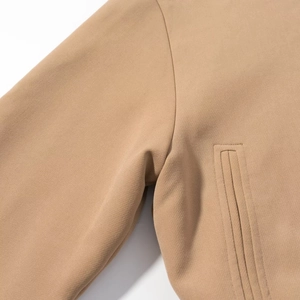 Détail de la couture de manche et poche passepoilée latérale sur veste kaki