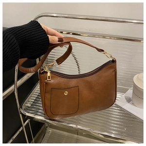 Detail of retro brown shoulder bag featuring gold hardware and front pocket design
