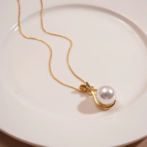 Detailed view of elegant gold pearl pendant with zircon inlay on a white plate