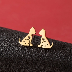 Macro view of gold cat stud earrings with hollow heart and star details on black leather