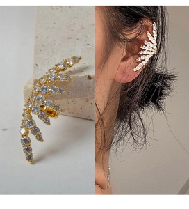 Detailed view of gold leaf ear cuff with micro-pave cubic zirconia on stone background