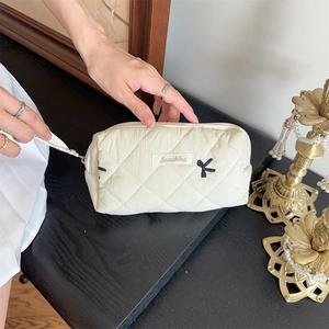 Detailed shot of the quilted makeup bag zipper with ribbon and embroidered Sezakka label