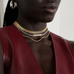 Macro shot of layered gold and silver chains paired with chunky silver hoop earrings