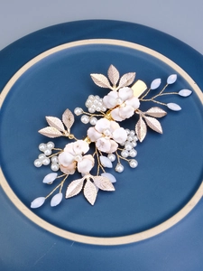 Detail of handmade floral bridal hair clip with gold leaves, white pearls and crystals