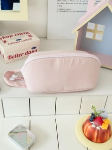 Close-up of pink fabric travel makeup bag with top zipper and portable handle design