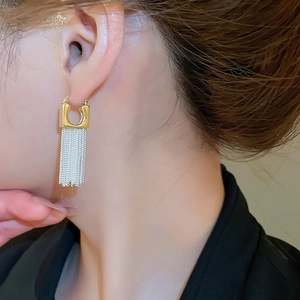 Detail view of gold square stud with silver chain tassels worn on a model ear