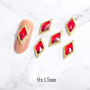 Detalle macro de adornos para uñas de rombo rojo de 9x15mm con marco metálico dorado