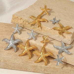 Golden and silver starfish earrings set in textured stainless steel on a stone pedestal