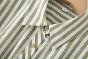 Dettaglio macro del colletto della camicia a righe verdi con bottoni dorati a sfera