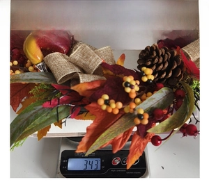 Detailed weight measurement of autumn wreath with maple leaves and pine cones showing 343g