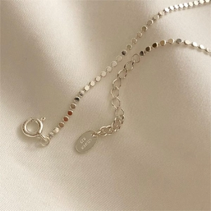 Detail of 925 sterling silver anklet with flat beads and hallmark engraving on soft cloth