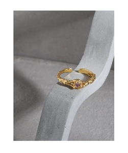 Macro detail of gold texture ring with pink zircon on grey artistic background