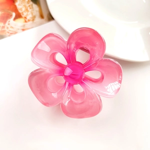 Detail showing translucent pink hollow frangipani hair claw clip on white backdrop