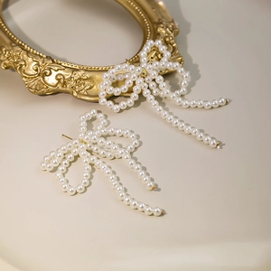 Macro shot of long tassel pearl bow earrings on a vintage gold frame backdrop