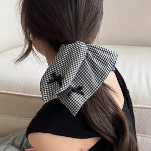 Detail of black and white checkered scrunchie with two small bows on a low ponytail