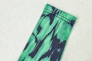 Close-up of green and blue abstract print on ribbed fabric with double-stitched hem
