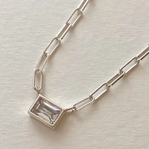 Macro shot of silver paperclip chain necklace with a rectangular clear zircon pendant