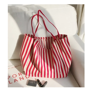 Close-up of red and white striped canvas tote bag on sofa with fashion magazines