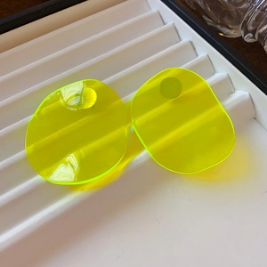 Detailed view of neon yellow irregular acrylic leaf earrings on a white jewelry tray