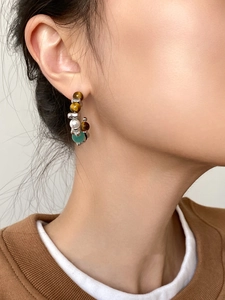 Close-up of a model wearing C-shaped earrings with cat eye and tiger eye stones