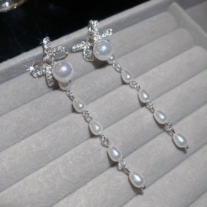 Detail of silver bow earrings with sparkling cubic zirconia, pearls, and long tassels