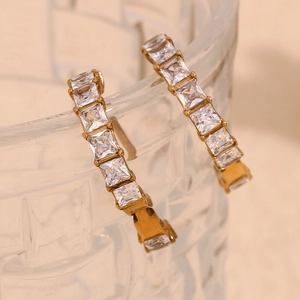 Vue détaillée des boucles d'oreilles dorées 18K avec zircons carrés sur verre ciselé