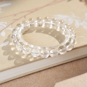Detail of clear crystal beaded bracelet on a floral vintage book with soft shadows