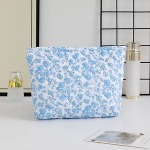 Close-up of blue floral quilted makeup bag with zipper closure and diamond stitching