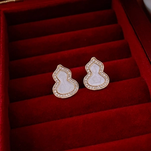 Détail macro de boucles d'oreilles gourde dorées avec incrustation blanche et zircon