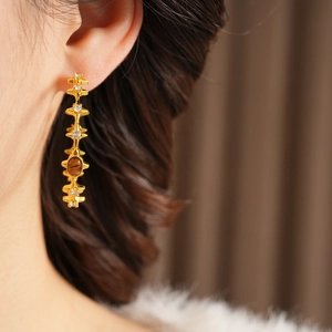 Detailed macro of gold vintage earrings featuring tiger eye stone and zircon inlays