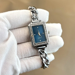 Detail of silver quartz watch featuring a rectangular blue dial with crystal bezel