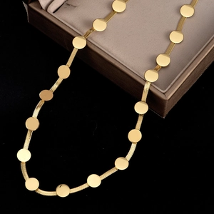 Détail d'un collier chaîne serpent dorée avec disques ronds plats dans un écrin à bijoux