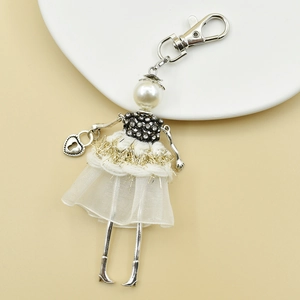 Detail of handmade cartoon doll keychain with pearl head, rhinestone body and gold tassels