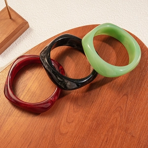Detail view of retro geometric resin bangles in red, black, and green marble patterns