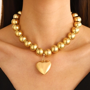 Exaggerated gold beaded necklace featuring a hollow heart pendant on a model