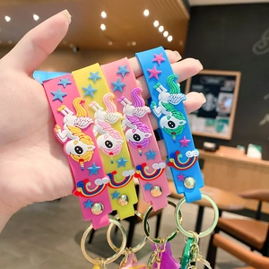 Hand holding colorful cartoon unicorn silicone keychains with rainbow star charms
