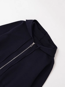 Close-up of a navy blue hooded cardigan featuring waffle knit texture and metal zipper
