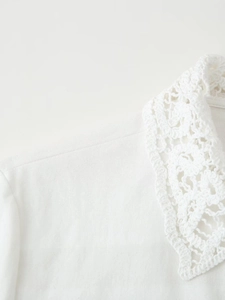 Vue détaillée du chemisier blanc avec col en dentelle crochetée et texture de coton