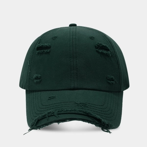 Close-up of distressed ripped details and cotton canvas texture on dark green baseball cap